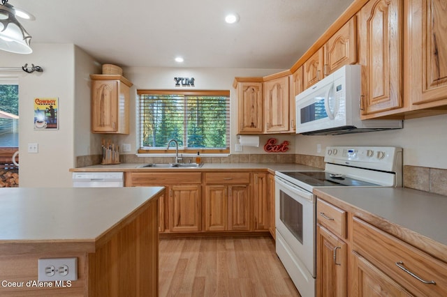 kitchen with sink, light brown cabinets, white appliances, and light hardwood / wood-style floors