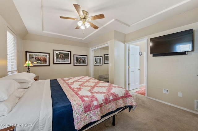 bedroom with ceiling fan, a raised ceiling, a closet, and carpet