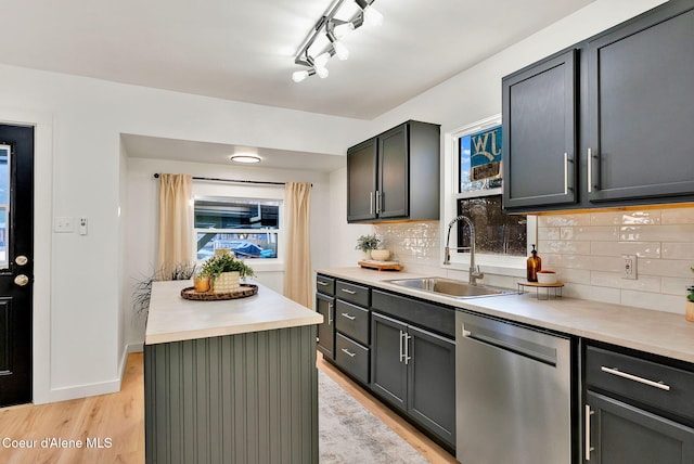 kitchen featuring sink, decorative backsplash, a center island, stainless steel dishwasher, and light wood-type flooring