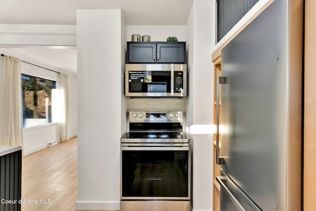 kitchen with stainless steel appliances, light hardwood / wood-style flooring, and decorative backsplash