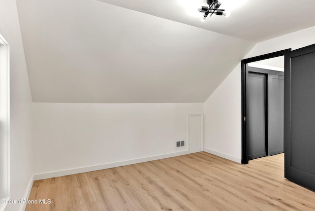 bonus room with lofted ceiling and light wood-type flooring