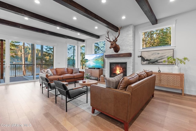 living room featuring beamed ceiling, a fireplace, and light hardwood / wood-style flooring