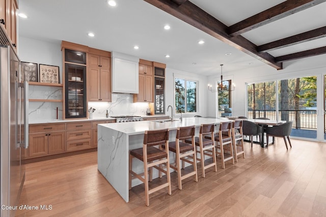 kitchen with plenty of natural light, stainless steel fridge, a kitchen island with sink, and decorative backsplash