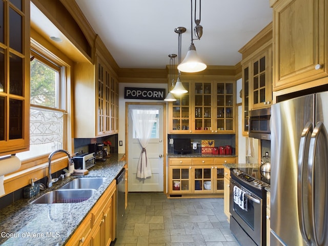 kitchen featuring sink, ornamental molding, appliances with stainless steel finishes, pendant lighting, and dark stone counters