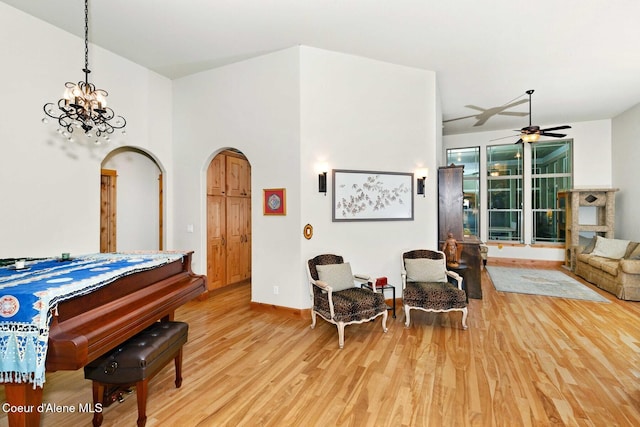 interior space featuring ceiling fan with notable chandelier and light wood-type flooring