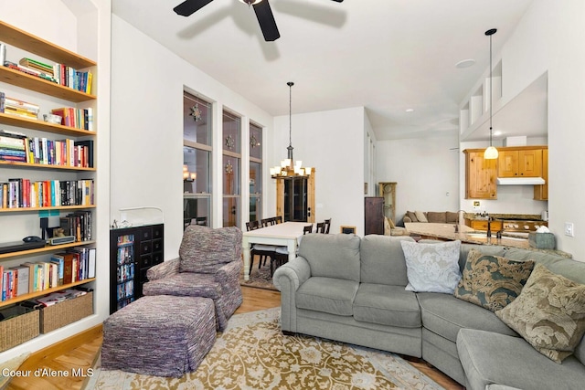 living room with ceiling fan with notable chandelier and light hardwood / wood-style floors