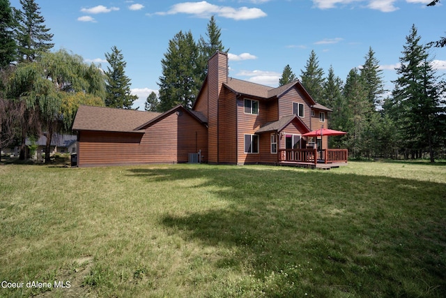 rear view of property with cooling unit, a wooden deck, and a yard