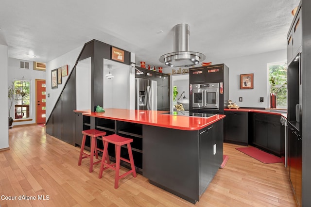 kitchen with a healthy amount of sunlight, appliances with stainless steel finishes, a breakfast bar area, and light hardwood / wood-style flooring