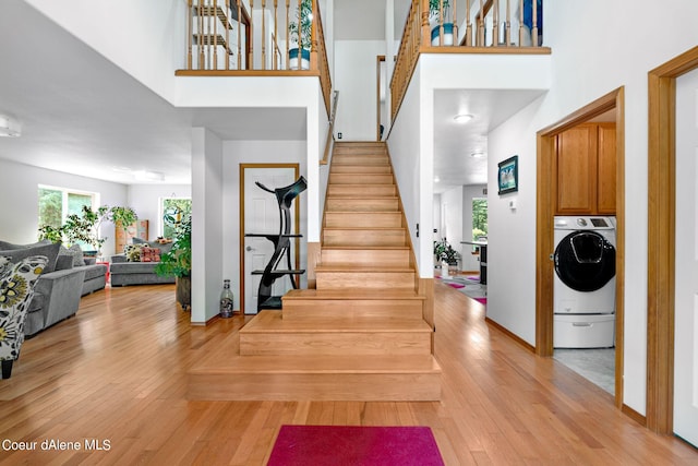 staircase featuring washer / dryer, hardwood / wood-style floors, and a high ceiling