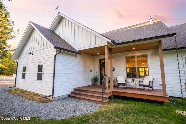 back house at dusk featuring covered porch