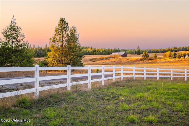 yard at dusk featuring a rural view