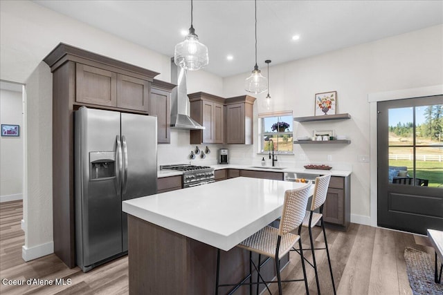 kitchen featuring pendant lighting, sink, stainless steel appliances, a center island, and light hardwood / wood-style floors