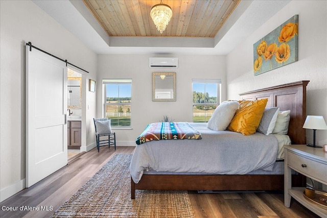 bedroom with ensuite bath, a barn door, a raised ceiling, and dark hardwood / wood-style flooring