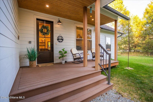 view of exterior entry featuring a lawn and a porch