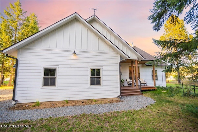 back house at dusk with a wooden deck and a yard