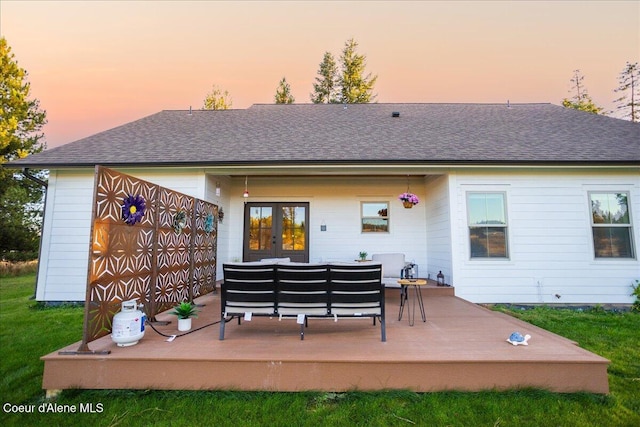 back house at dusk featuring a wooden deck, outdoor lounge area, and french doors