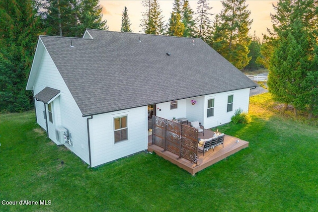 back house at dusk with a wooden deck and a yard