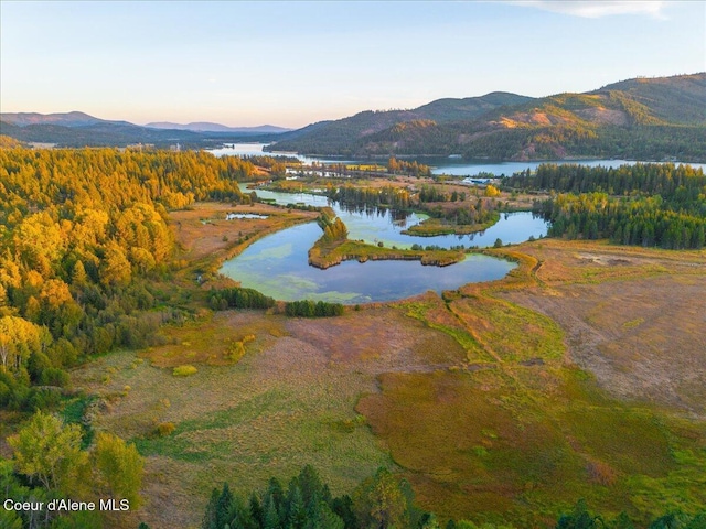 aerial view at dusk featuring a water and mountain view