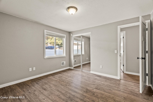 unfurnished bedroom with dark wood-type flooring, a closet, and a textured ceiling