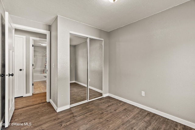 unfurnished bedroom featuring a closet, dark hardwood / wood-style floors, and a textured ceiling