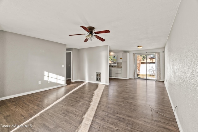 unfurnished living room featuring dark wood-type flooring and ceiling fan