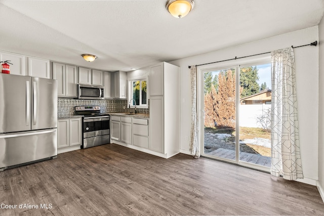 kitchen featuring sink, backsplash, stainless steel appliances, dark wood-type flooring, and a textured ceiling