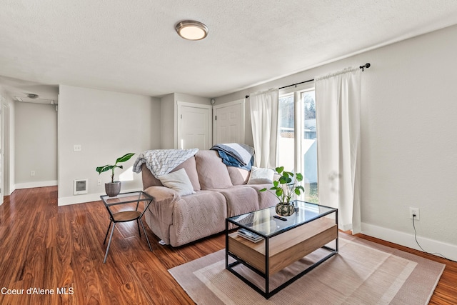 living room featuring dark wood-type flooring and a textured ceiling