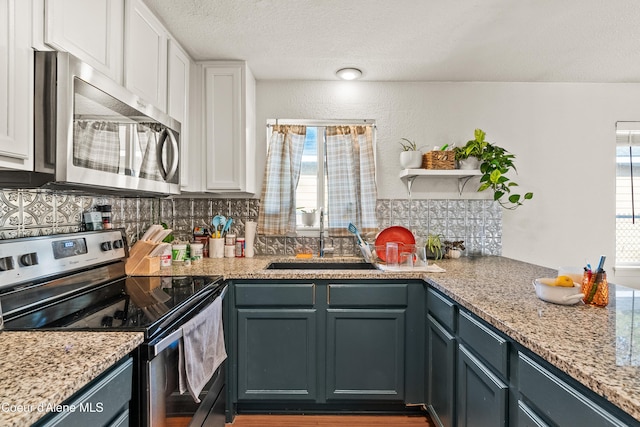 kitchen with sink, appliances with stainless steel finishes, light stone countertops, white cabinets, and decorative backsplash