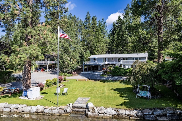 rear view of house featuring a deck with water view and a yard