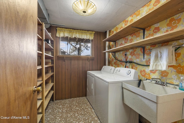 washroom with sink, wooden walls, and independent washer and dryer