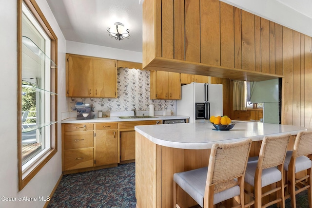 kitchen with a kitchen bar, sink, and white fridge with ice dispenser