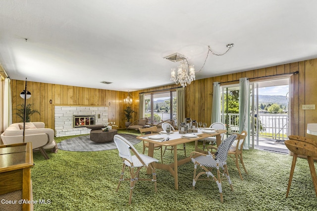 dining area with a stone fireplace, wood walls, and carpet