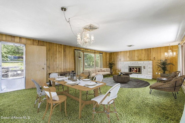 dining area featuring carpet flooring, wooden walls, and a chandelier