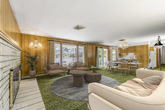 carpeted living room with a stone fireplace, a notable chandelier, and wooden walls