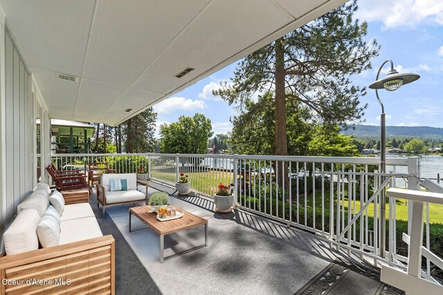 view of patio featuring an outdoor living space, a balcony, and a water view