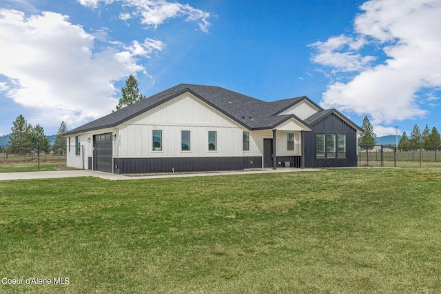 modern farmhouse featuring fence, concrete driveway, and a front yard