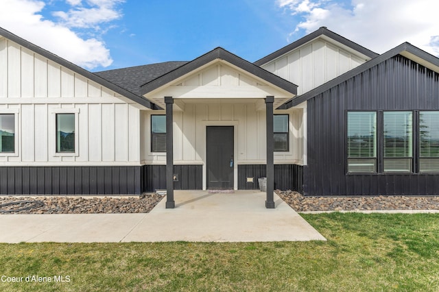 view of front of house featuring a patio, a shingled roof, board and batten siding, and a front lawn