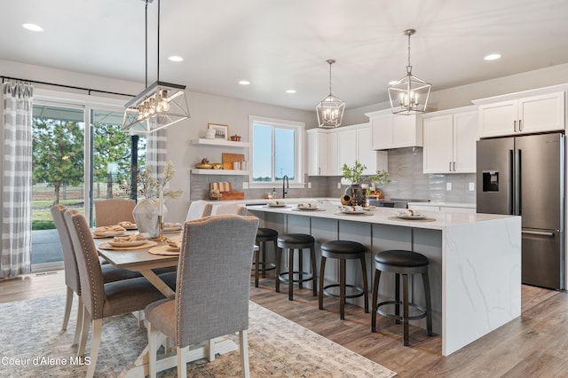 kitchen featuring white cabinetry, a kitchen island, stainless steel fridge, and decorative light fixtures