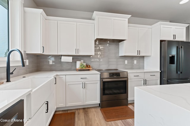 kitchen with electric range, white cabinetry, and black refrigerator with ice dispenser