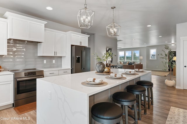 kitchen featuring decorative light fixtures, a breakfast bar area, white cabinets, a center island, and stainless steel appliances