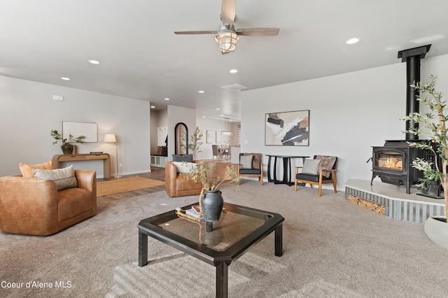 living area with carpet floors, recessed lighting, a wood stove, and ceiling fan