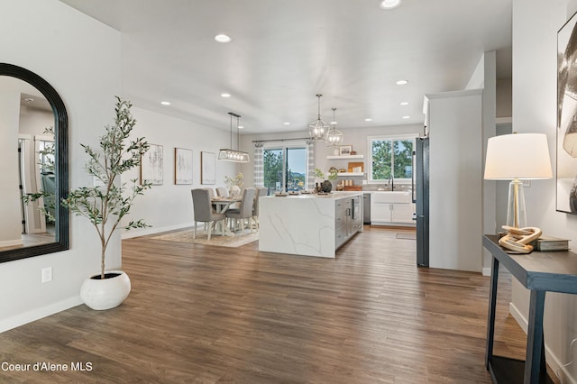 kitchen with dark hardwood / wood-style floors, decorative light fixtures, white cabinetry, a center island, and light stone counters