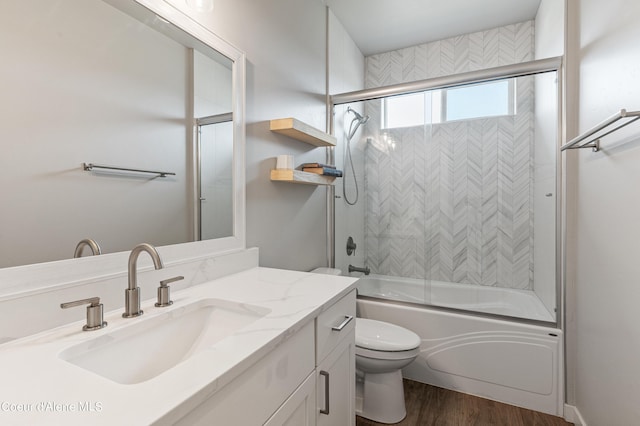 bathroom with toilet, bath / shower combo with glass door, wood finished floors, and vanity