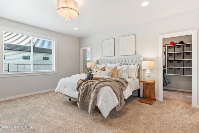 bedroom with a walk in closet, recessed lighting, light carpet, a chandelier, and baseboards