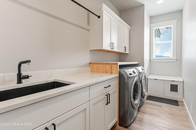 clothes washing area with cabinet space, light wood finished floors, independent washer and dryer, a sink, and recessed lighting