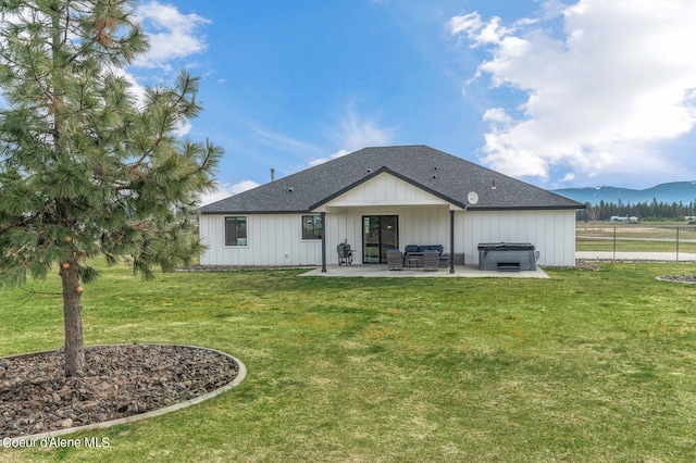 rear view of house featuring a mountain view, a lawn, a hot tub, and a patio