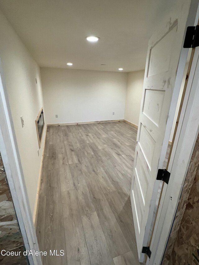 below grade area featuring recessed lighting, heating unit, baseboards, and wood finished floors