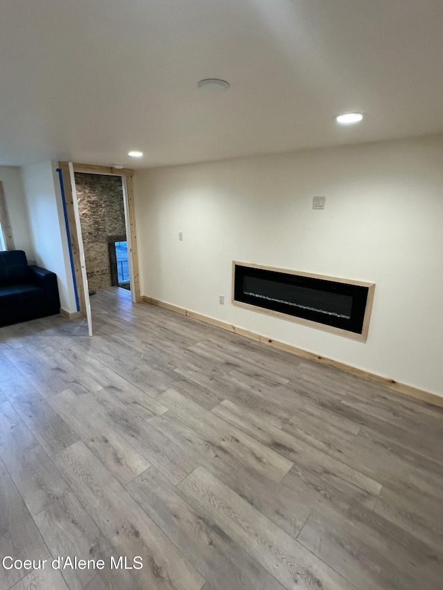 unfurnished living room with recessed lighting, a fireplace, baseboards, and wood finished floors