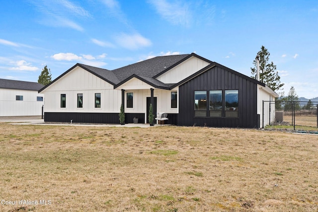 modern farmhouse featuring a front lawn, fence, and board and batten siding