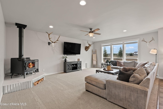 carpeted living room featuring recessed lighting, baseboards, a wood stove, and ceiling fan